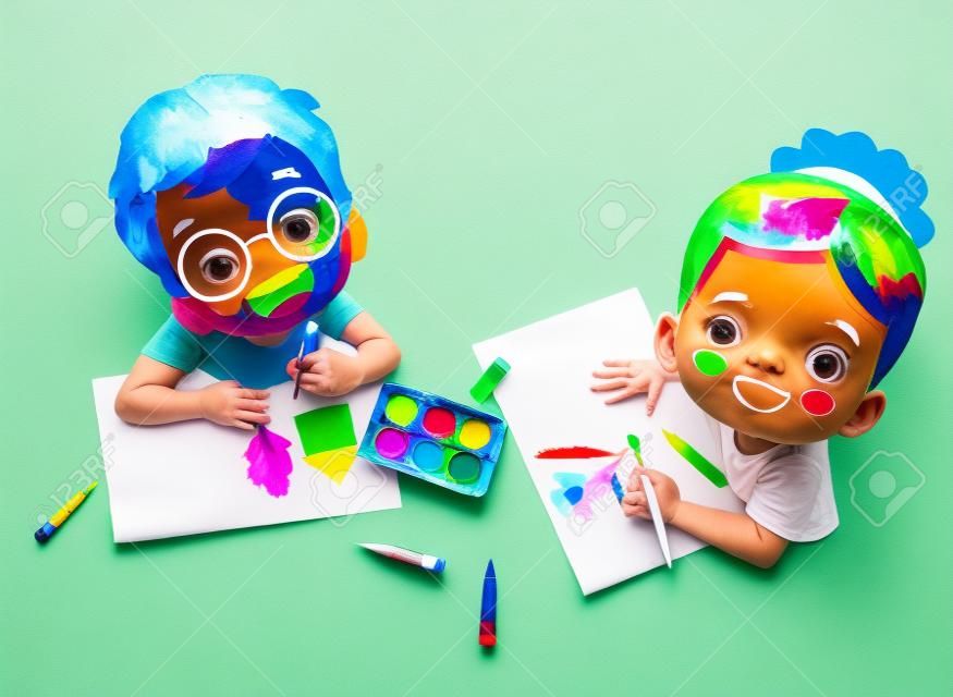 Enfants coupant du papier de couleur avec des ciseaux et de la peinture