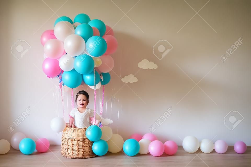 Decorative balloon basket, birthday, party. A little girl dreams of flying in a hot air balloon. Emotions are joy, fun. The natural light, the sun's rays.