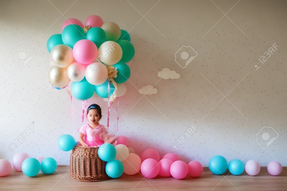 Dekoracyjny kosz balonowy, urodziny, impreza. mała dziewczynka marzy o lataniu balonem. emocje to radość, zabawa. naturalne światło, promienie słoneczne.