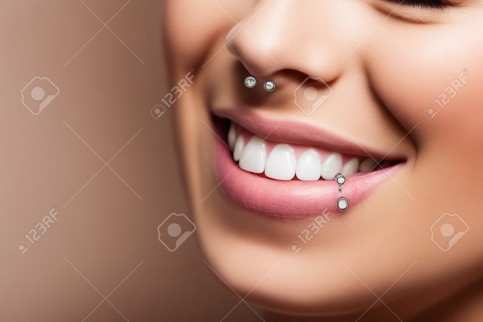 Toothy smile. Woman with piercing in nose and lip. Unrecognizable
