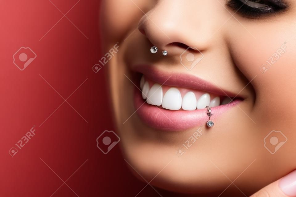 Toothy smile. Woman with piercing in nose and lip. Unrecognizable