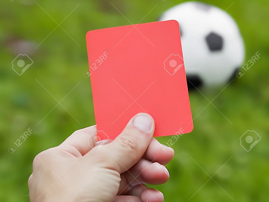 Hand omhoog rode kaart tegen voetbalveld