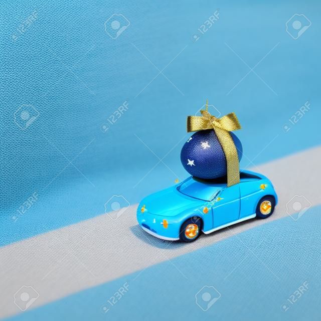 Toy car transport blue egg decorated with stars. Original idea for easter decor. Creative minimal easter concept