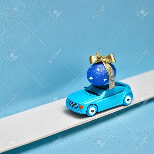 Toy car transport blue egg decorated with stars. Original idea for easter decor. Creative minimal easter concept