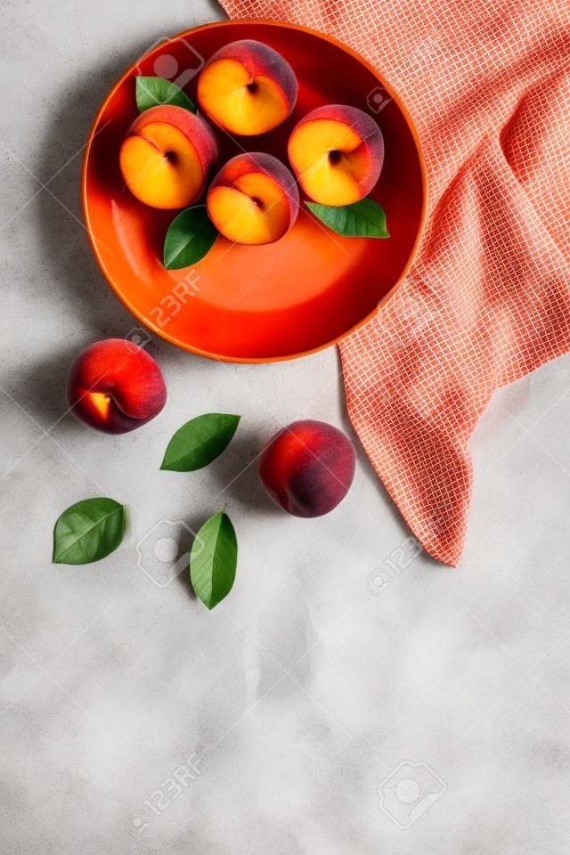 Summer lunch. Red peaches on white background with tablecloth and leaves top-down.