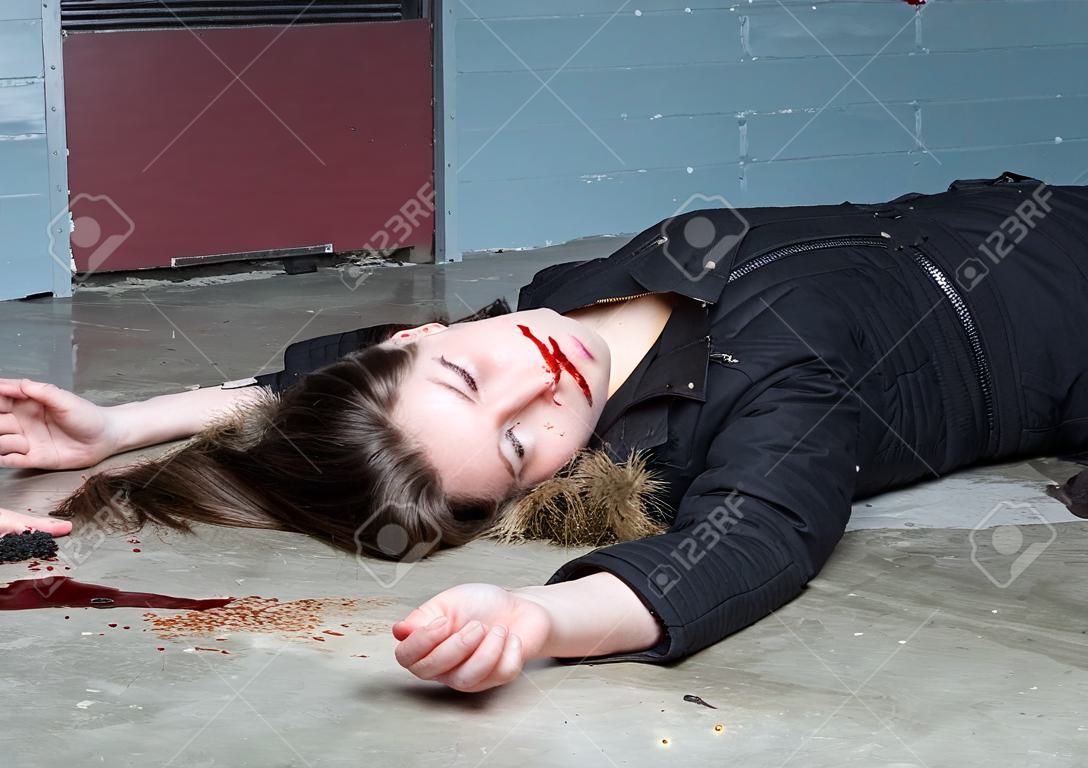 Assassinato donna su un pavimento di calcestruzzo seminterrato con sangue splatter e sangue in una scena del crimine fresche