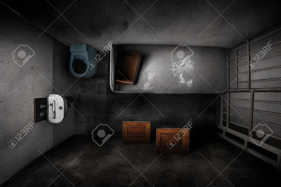 침대, 싱크대, 화장실, 의자 한 사람이 잠긴 오래된 감옥의 상위 뷰입니다. 어두운 분위기.