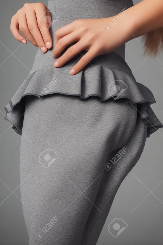 Belle jeune fille en jupe courte sur fond gris.