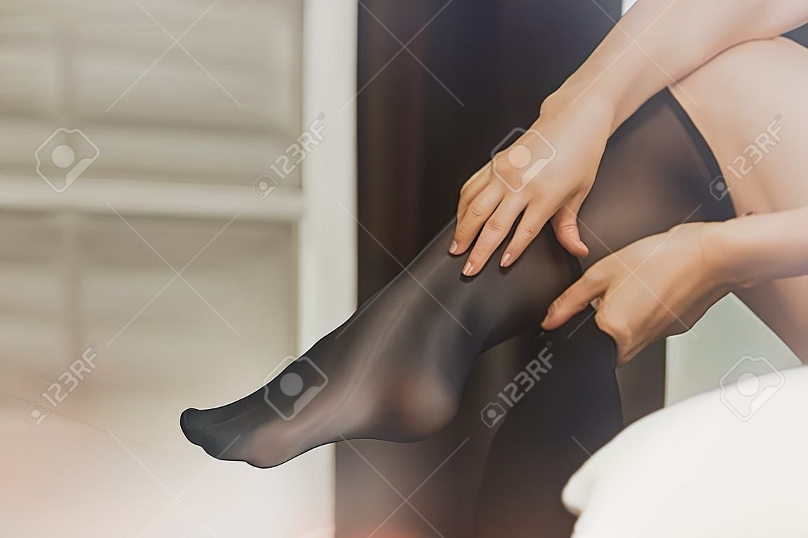 Woman in bedroom dressing pantyhose