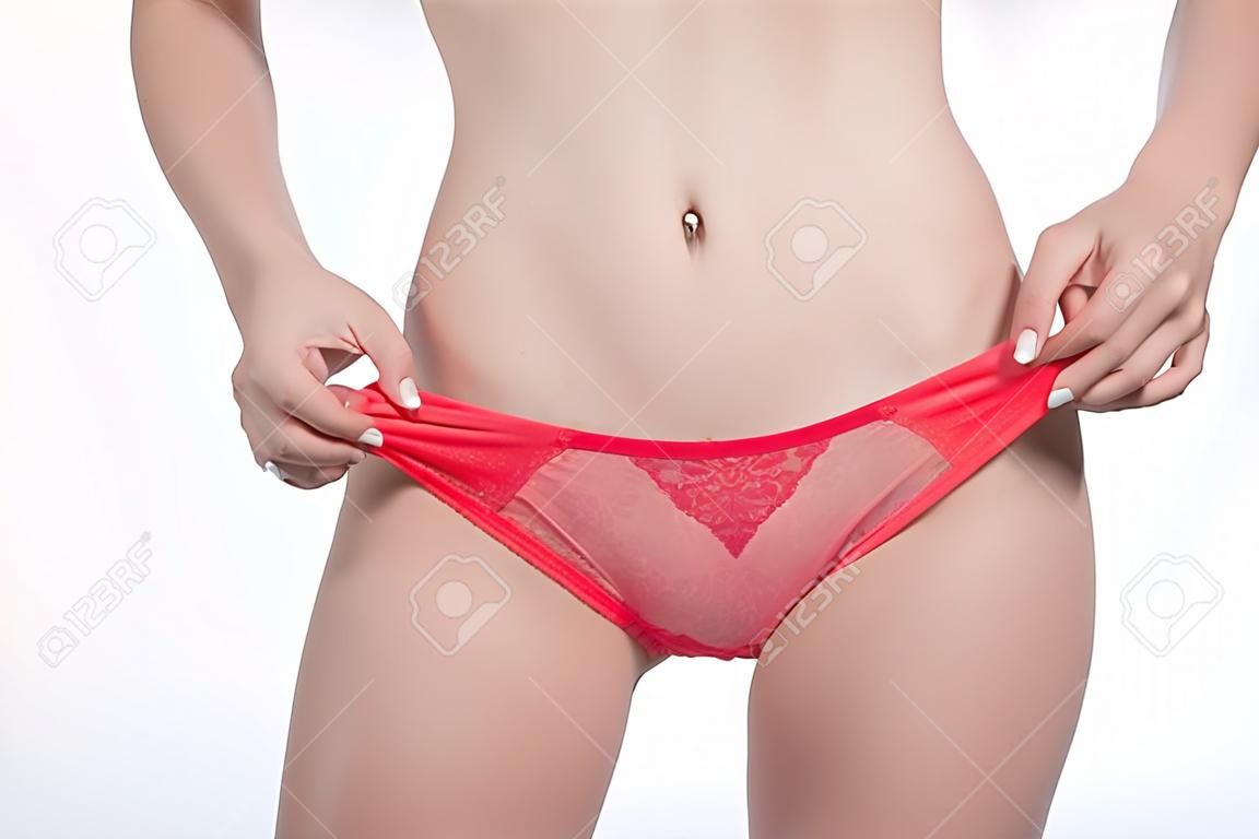 Crop female in underwear adjusting lace panties while standing on white background