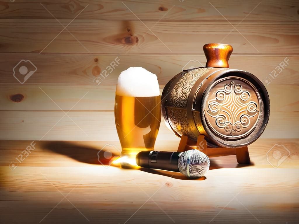 Barrel and glass of beer, microphone on wooden background. concept karaoke.