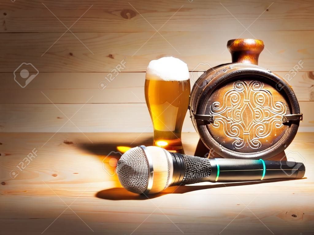 Barrel and glass of beer, microphone on wooden background. concept karaoke.