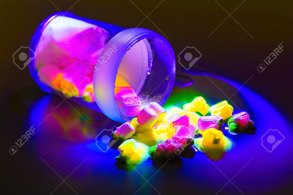 Materiali organici fluorescenti come una polvere di colore rosso, giallo e verde per la produzione di OLED all'interno di una bottiglia di vetro in luce UV.