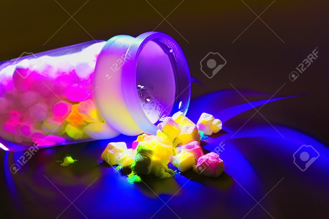 Materiali organici fluorescenti come una polvere di colore rosso, giallo e verde per la produzione di OLED all'interno di una bottiglia di vetro in luce UV.