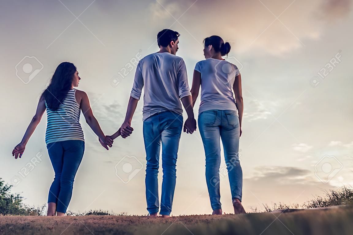 Immagine a figura intera di belle coppie romantiche godendo la compagnia a vicenda all'aperto e tenendo le mani sullo sfondo del cielo.