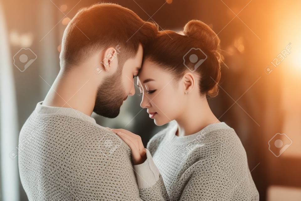 Le coppie romantiche appassionate in maglioni trascorrono del tempo insieme prima del nuovo anno a casa