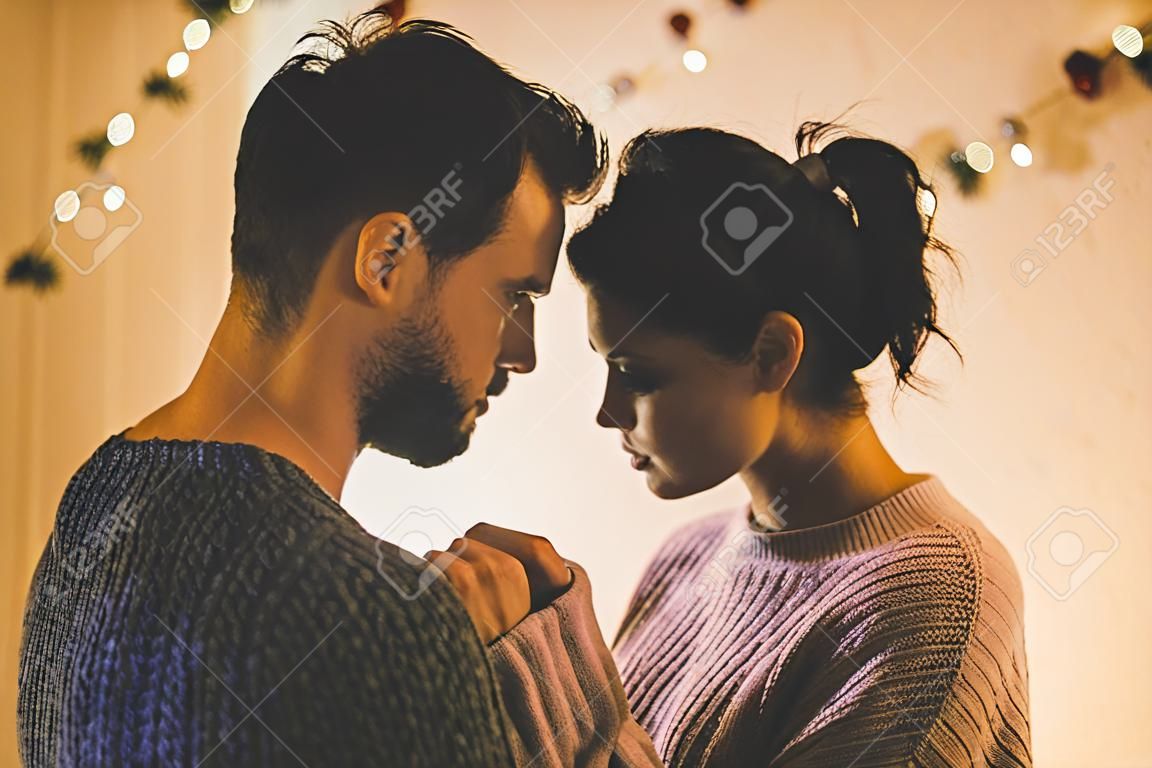 Passionate romantic couple in sweaters are spending time together before New Year at home