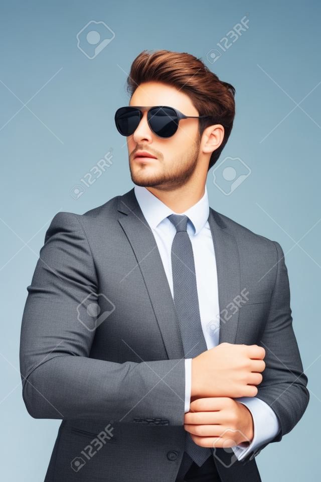 Portrait of young handsome businessman is standing in official clothes and sunglasses. Confident and successful man in suit.