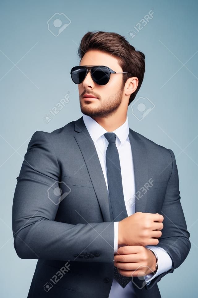 Portrait of young handsome businessman is standing in official clothes and sunglasses. Confident and successful man in suit.
