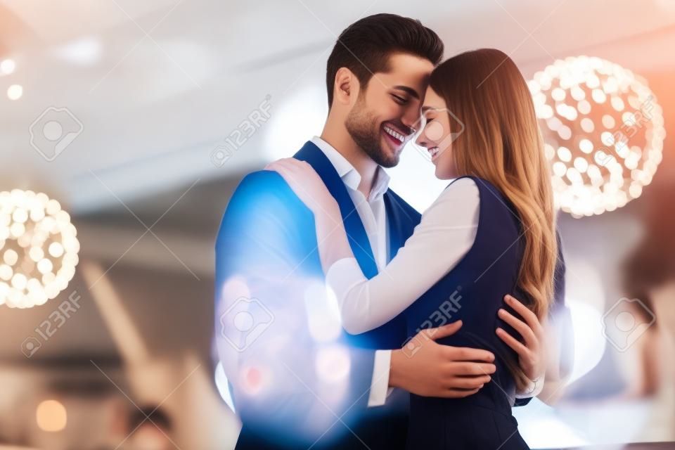 美丽的恋人在现代餐厅共度时光，迷人的年轻女子穿着礼服，英俊的男士穿着浪漫的晚餐庆祝情人节。