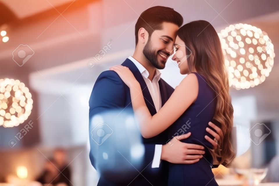 Hermosa pareja amorosa es pasar tiempo juntos en un restaurante moderno. La mujer joven atractiva en vestido y el hombre hermoso en traje están cenando romántico. Celebrando el día de san valentín.