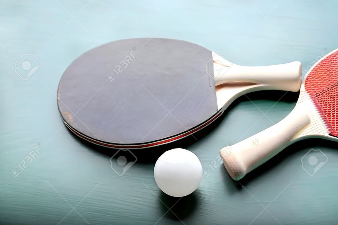 Table tennis rackets with ball on green background
