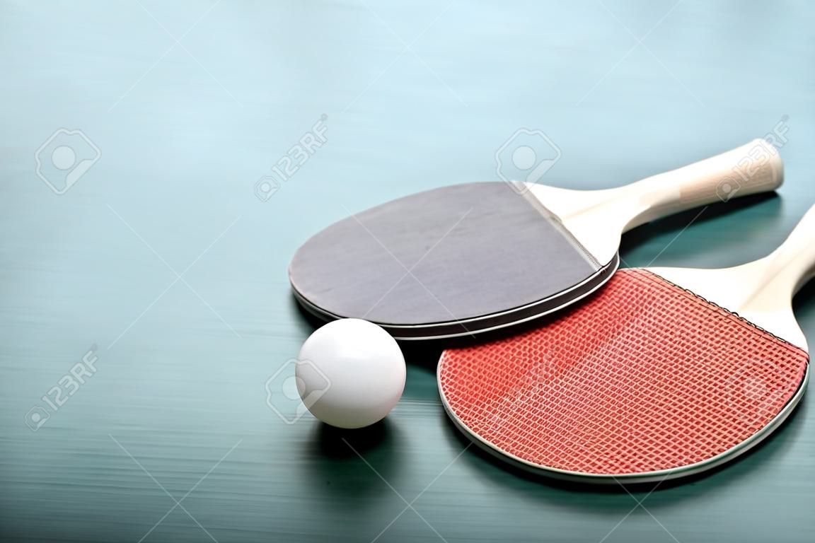 Raquetas de tenis de mesa con pelota sobre fondo verde