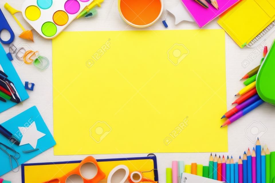 Different school supplies with blank sheet of paper on yellow