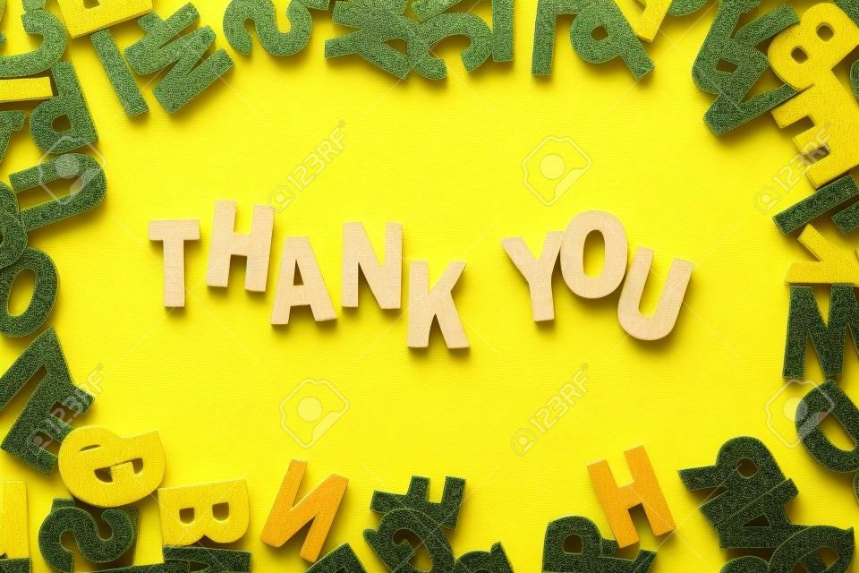 Word Thank You by wooden letters on yellow background
