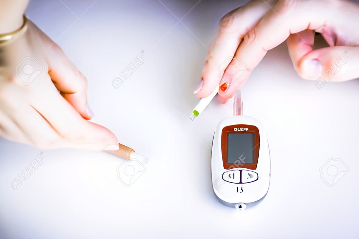 Close-up Of Woman Hands Testing High Blood Sugar With Glucometer, Blood glucose meter, The blood sugar value is measured on a finger, Syringe pen with insulin and glucometer
