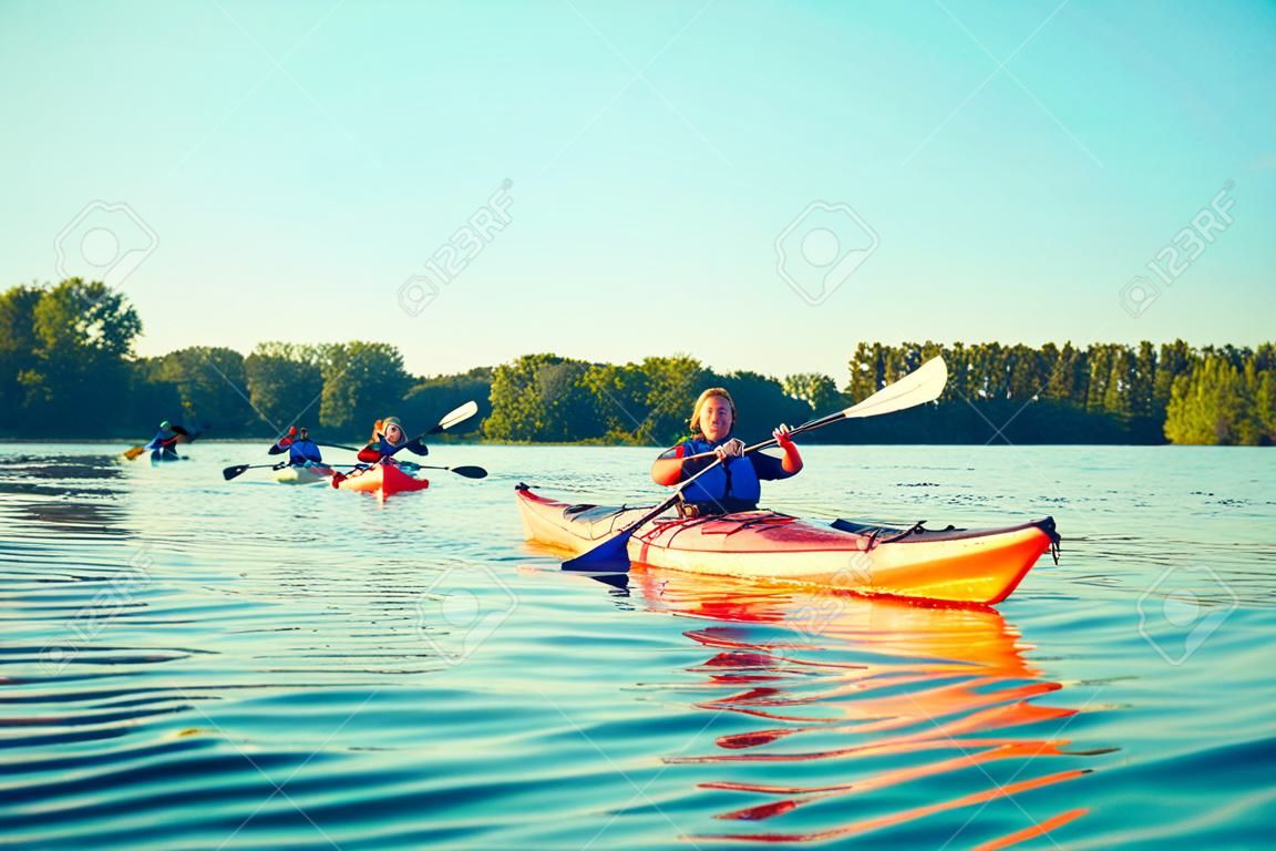 Kayaking couple ride along the river at sunset