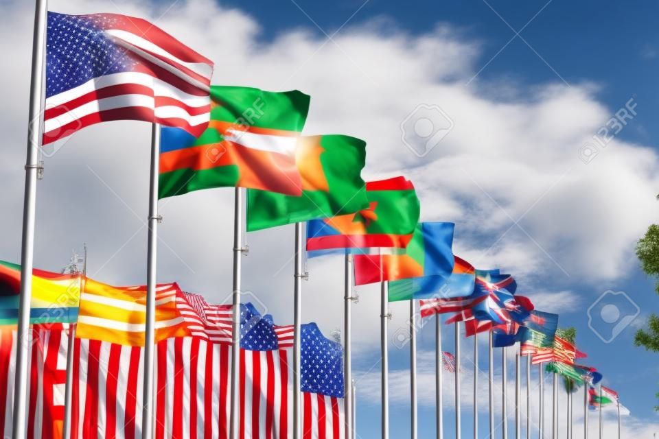 Waving national flags of different countries on flagpoles on the background of urban buildings