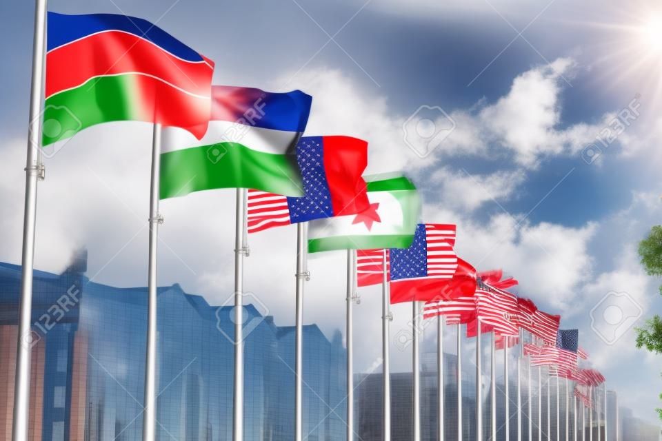 都市の建物の背景に旗竿に異なる国の国旗を振る