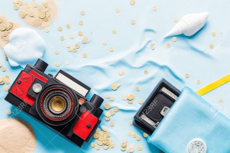 Enjoying vacation mood, a roll film vintage camera and money purse on white sand background. Space for a text or product display, top view.