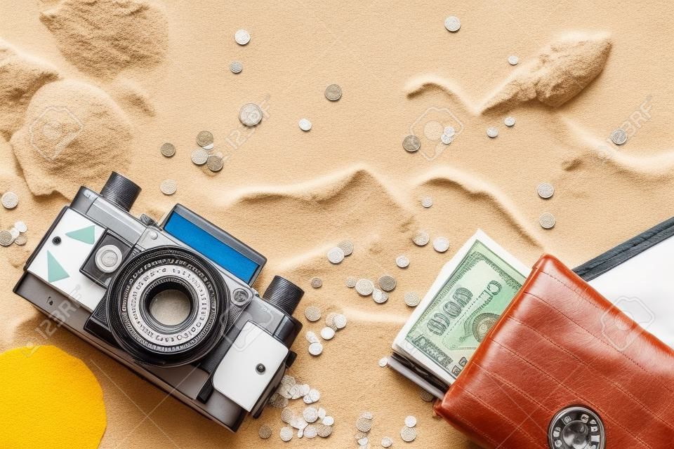Enjoying vacation mood, a roll film vintage camera and money purse on white sand background. Space for a text or product display, top view.