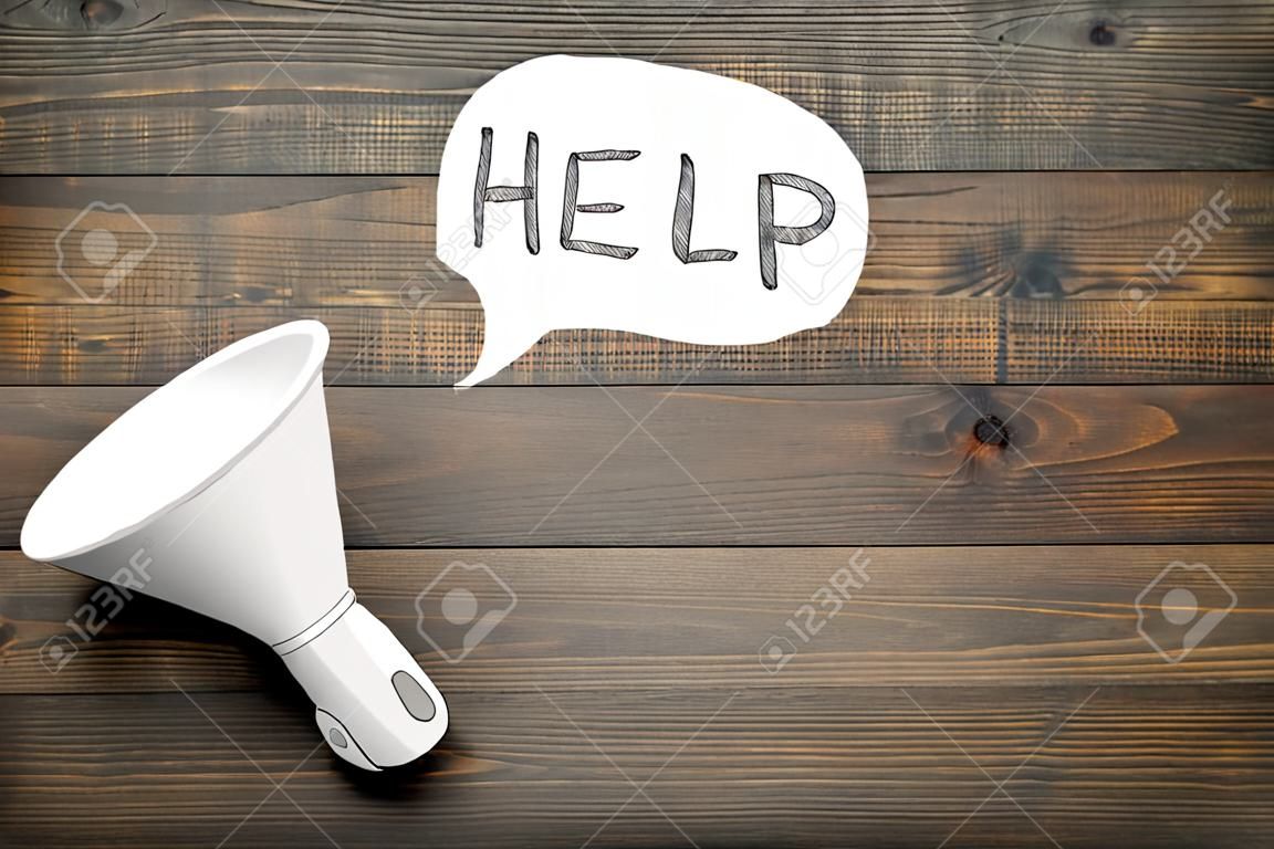 Call for help concept. Megaphone near cloud with word help on dark wooden background top view.