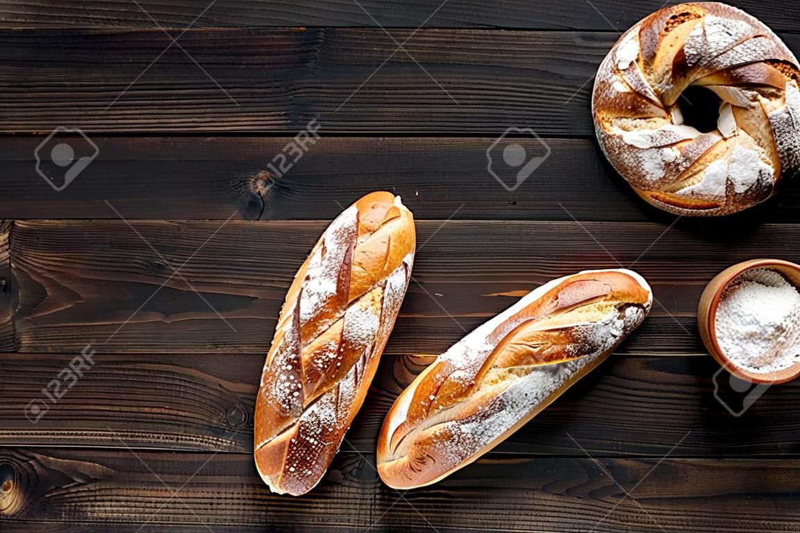 Apetitoso concepto de pan fresco. Baguette y pan redondo en la vista superior de fondo de madera oscura.