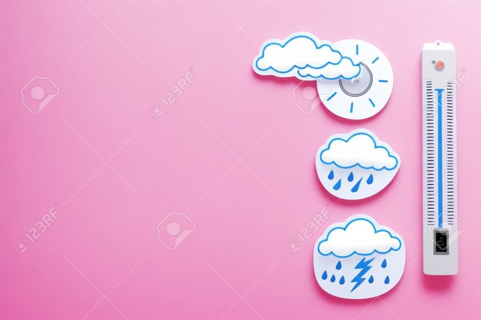 天気予報のコンセプト。大気温。ピンクの背景に雲と稲妻、太陽、雨雲の間の温度計上面図コピースペース