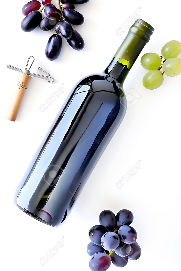 Concetto di vino rosso. Bottiglia di vetro con bevanda vicino a grappolo d'uva e cavatappi su sfondo bianco vista dall'alto.