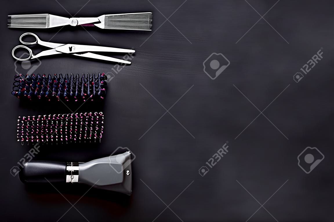 Hairdresser equipment for cutting hair and styling with combs, scissors, brushes on black background top view copyspace