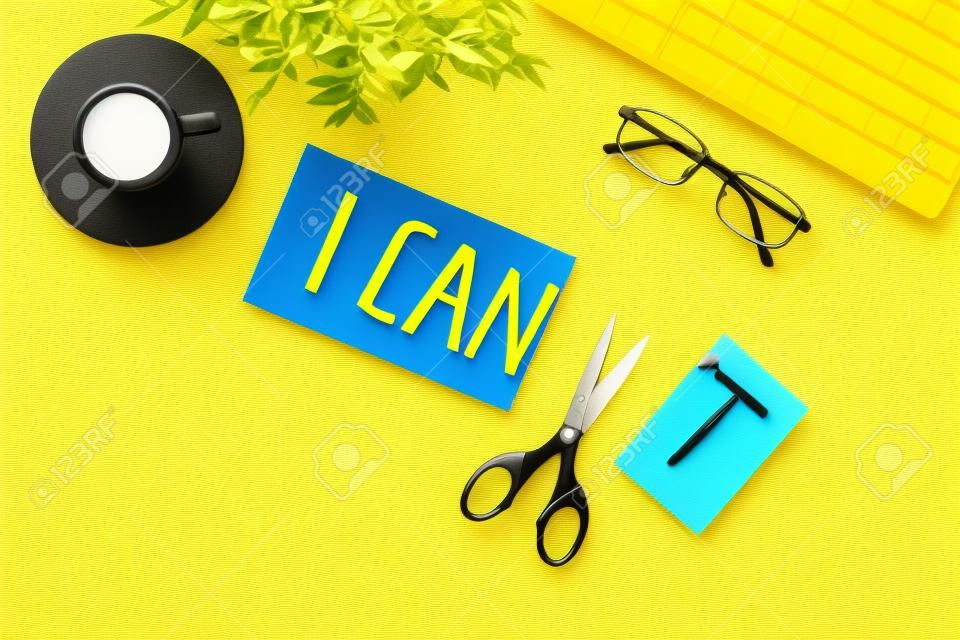 Motivation to be confident. Cut text I can't near scissors on yellow office desk.