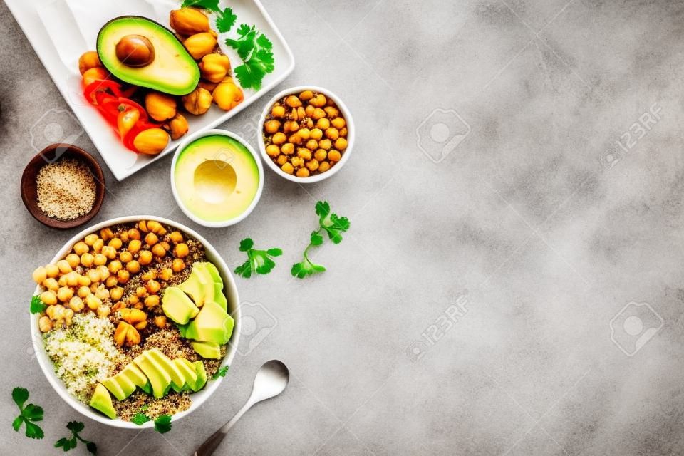 Quinoa, avocado and chickpeas in bowl in hands - balanced healthy food - on white table. Top view copy space