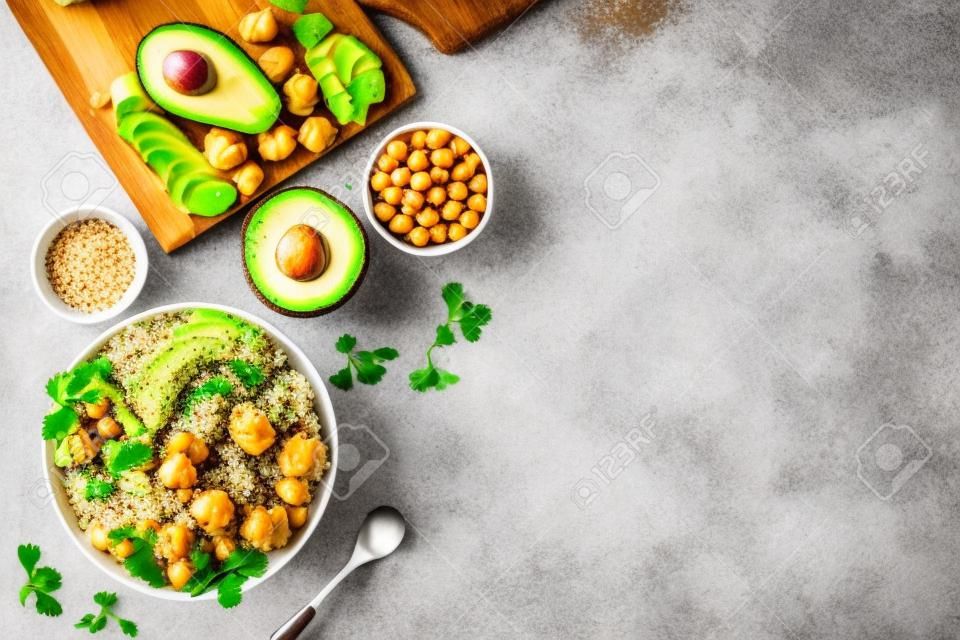 Quinoa, avocado and chickpeas in bowl in hands - balanced healthy food - on white table. Top view copy space