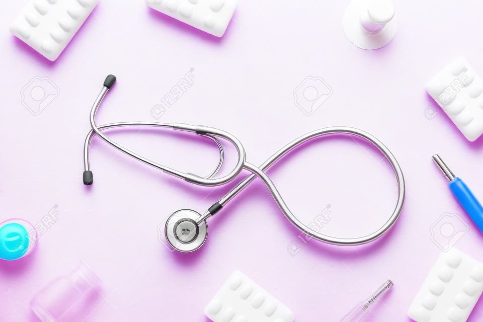 Flu treatment concept with medicine and stethoscope pink background top view copy space