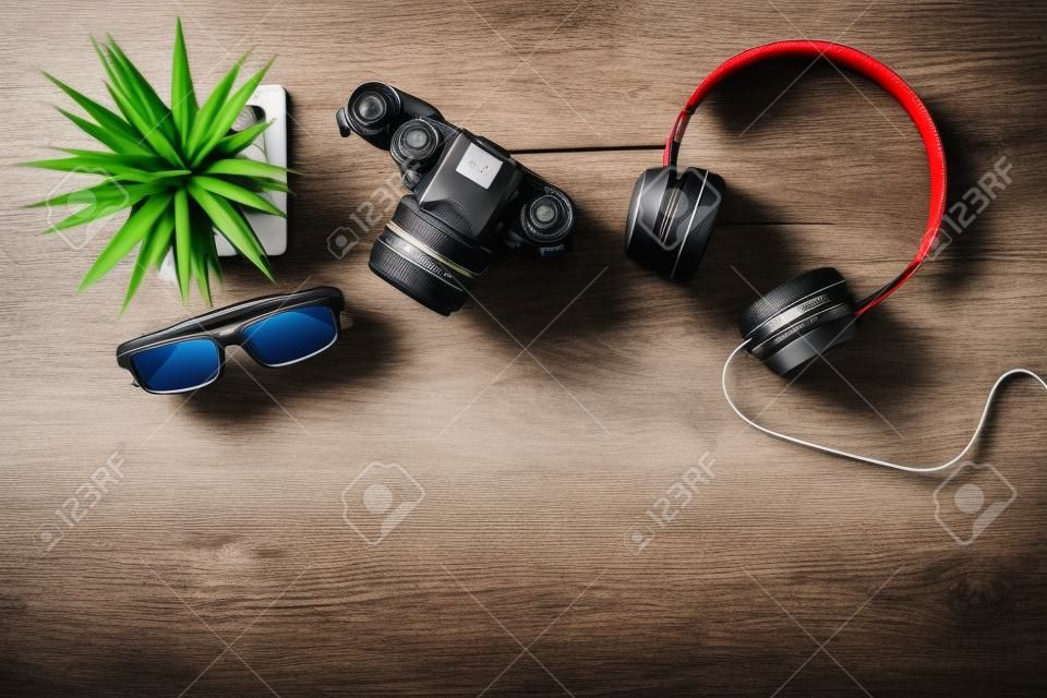 Top view of travel stuff. Camera, headphones and glasses on wood table with copy space