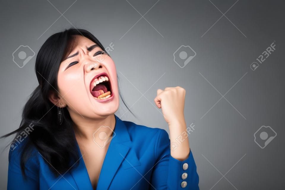 angry woman shouting, screaming with upset mood; portrait of angry upset asian woman shouting or screaming to blank space; harsh and loud noise shouting communication concept; asian adult woman model
