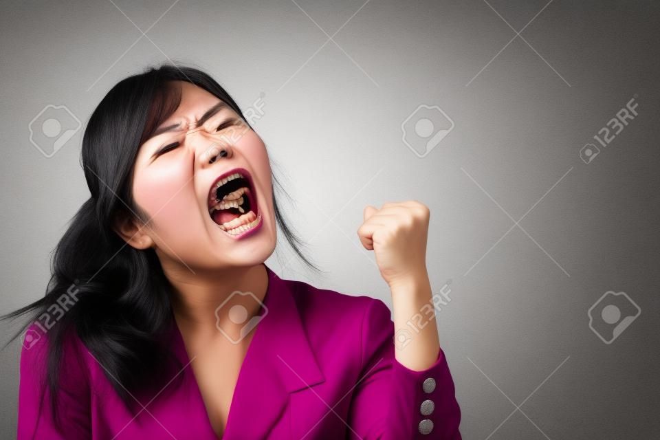angry woman shouting, screaming with upset mood; portrait of angry upset asian woman shouting or screaming to blank space; harsh and loud noise shouting communication concept; asian adult woman model