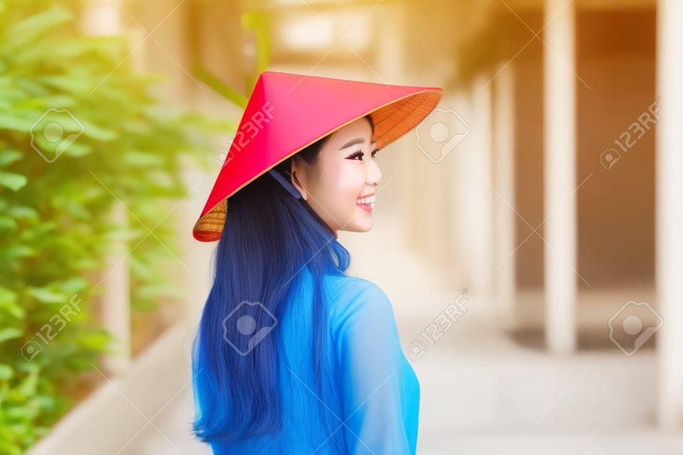 Happy smiling Vietnamese girl; portrait of exotic asian Vietnam woman in traditional Vietnamese Ao Dai dress