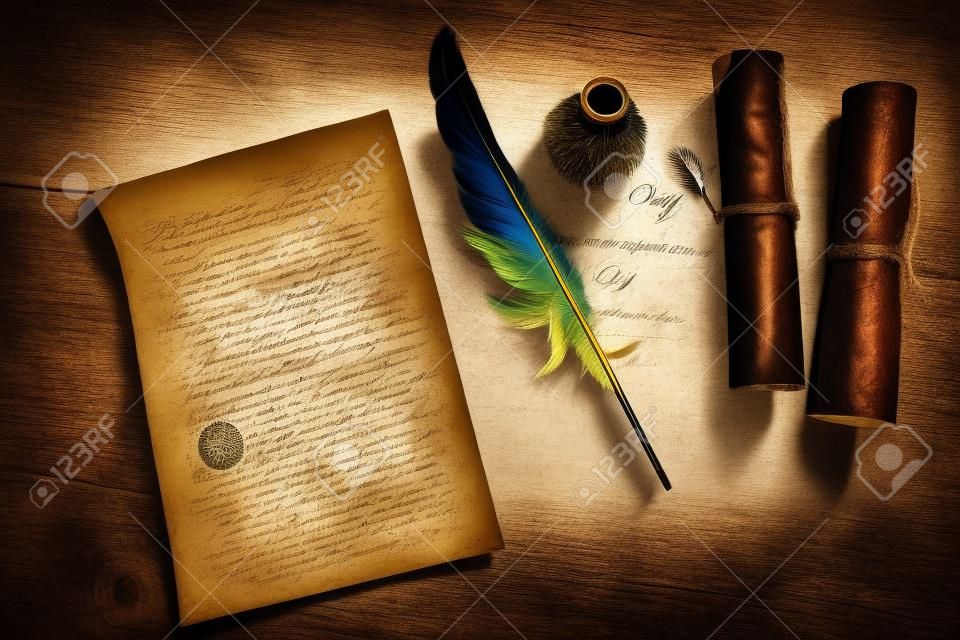 Quill pen, feather with a letter and a scroll on a wooden table. Vintage concept