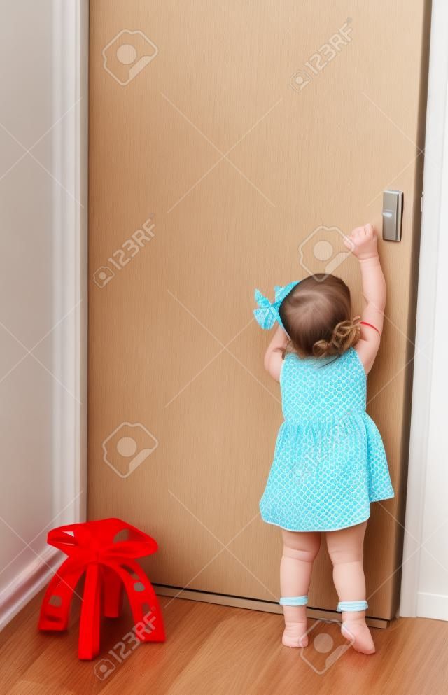 Aranyos kis baba lány próbál megnyitni ajtók
